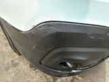 the front bumper of a white car with a dent on it