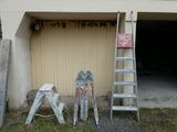 several ladders are leaning against a garage door and a ladder leaning against a garage door
