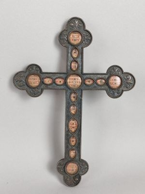 un gros plan d'une croix posée sur une surface blanche, sur laquelle figurent de nombreux visages