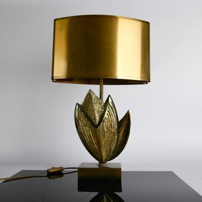 lampe de table en feuille d'or posée sur une table noire, avec un abat-jour doré
