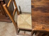a wooden table with two chairs next to a piano