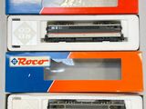 trois cartons contenant des trains miniatures posés sur une table