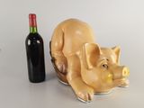 a pig figurine next to a bottle of wine on a table