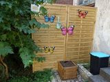 a wooden fence with butterflies on it next to a planter