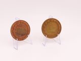 two small coins sitting on top of each other on a white surface