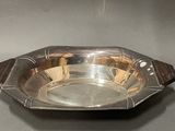 une assiette ancienne en argent avec un manche en bois sur un fond gris