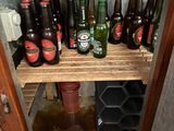 bottles of beer are lined up on a wooden shelf in a bathroom