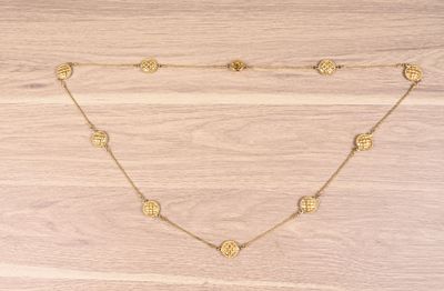 a gold necklace with coins on a wooden surface