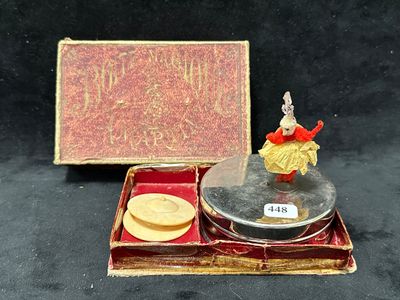 une petite figurine dans une boîte, accompagnée d'une boîte de biscuits