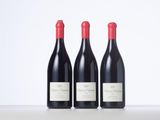 three bottles of red wine are lined up on a table