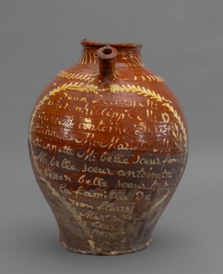 un vase marron portant une inscription, posé sur une surface grise
