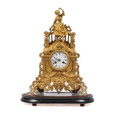 une horloge dorée posée sur un socle, sur fond blanc