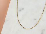 un collier à chaîne en or posé sur une surface en marbre
