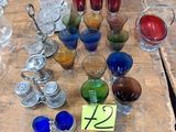 de nombreux objets en verre de différentes couleurs posés sur une table en bois