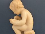 statue of a boy sitting on a box reading a book