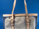 someone is holding a gray and tan bag on a blue background