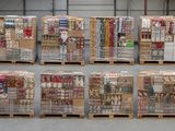 Plusieurs palettes contenant des articles variés sont empilées dans un entrepôt.
