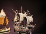 two models of a boat on display on a purple surface