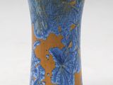 un vase bleu et orange posé sur une surface blanche