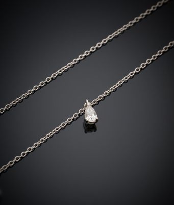un pendentif orné d'un seul diamant est suspendu à une chaîne posée sur une surface noire