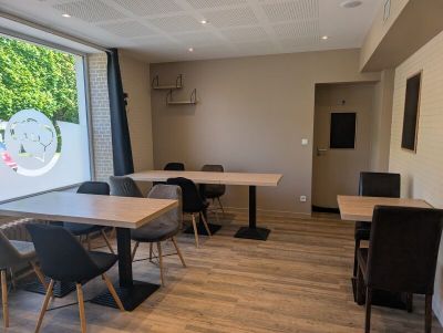 des tables et des chaises dans une pièce dotée d'une grande fenêtre donnant sur l'extérieur