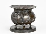 a silver vase with a dragon on it on a stand
