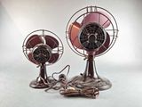two metal fans sitting next to each other on a table