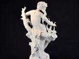 a white statue of a man sitting on top of a tree branch