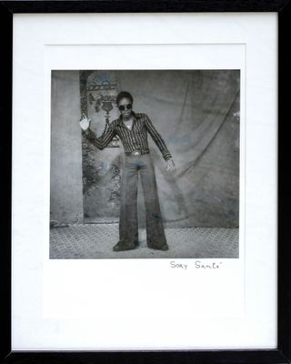 an old photo of a man in a suit and sunglasses holding a camera