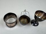 three silver cups and spoons sitting on a white surface