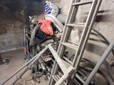 une échelle appuyée contre un mur, à côté d'un tas de métal