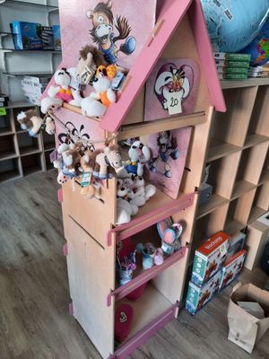 une maison de poupées en bois sur laquelle sont posés de nombreux animaux en peluche