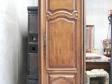 une grande armoire en bois, dans une pièce, à côté d'une chaise