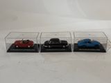 three miniature cars are in a display case on a white surface