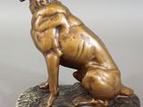 bronze statue of a dog sitting on a rock with its head in its paws