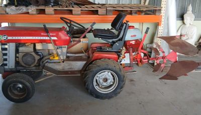 un tracteur rouge garé dans un garage, équipé d'une charrue