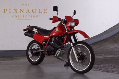 a red motorcycle parked in front of the pinnacle collection sign