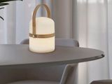 une table sur laquelle se trouve une lampe, avec une chaise placée devant une fenêtre
