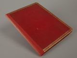 an old red book sitting on top of a white table