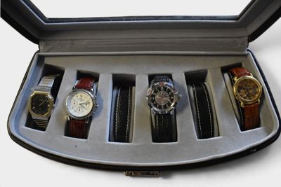 cinq montres dans un coffret posé sur une surface blanche