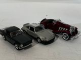 three toy cars sitting next to each other on a white surface