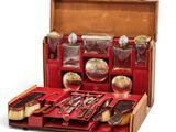 a red suitcase with silverware in it on a white surface