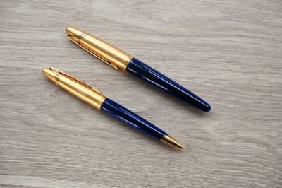 two pens sitting on top of a wooden table next to each other