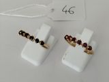 a pair of white and gold rings with garnets on them