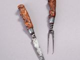 two knives with carvings on them sitting next to each other on a white surface