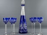 four wine glasses and a decanter on a table