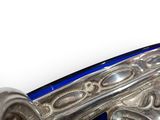 a close up of a blue glass vase with a silver handle