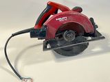 une scie circulaire rouge posée sur une surface blanche