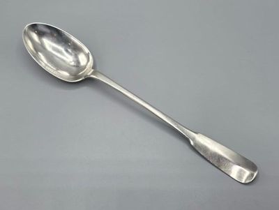 cuillère en argent à long manche posée sur une surface grise