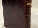 un vieux livre en cuir marron posé sur une nappe blanche